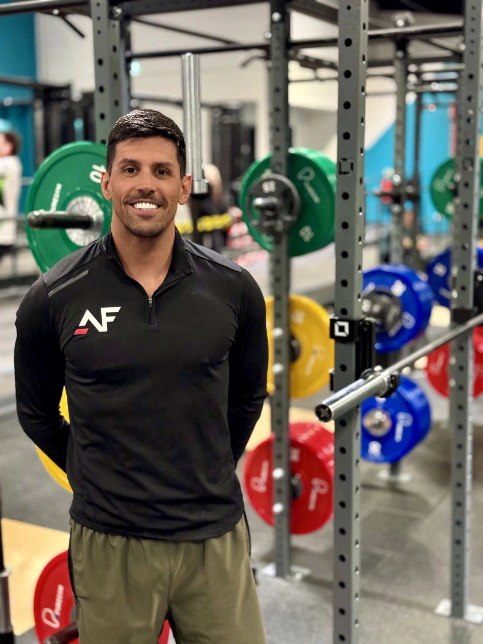 Andres Lopez in the gym, smiling beside the training equipment